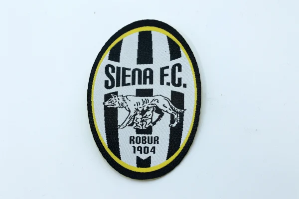 Toppa ufficiale del Siena FC con logo Robur 1904 su sfondo bianco.